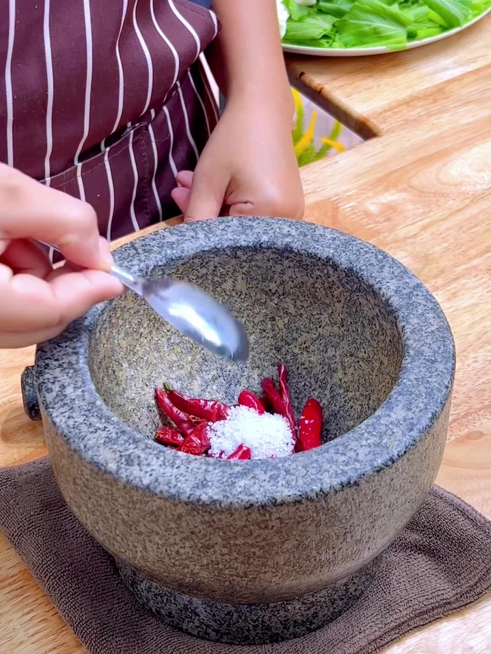 Prepare the curry paste: Pound dried and fresh chilies (adjust to your spice preference), lemongrass, and shallots roughly in a mortar and pestle. (139.76)